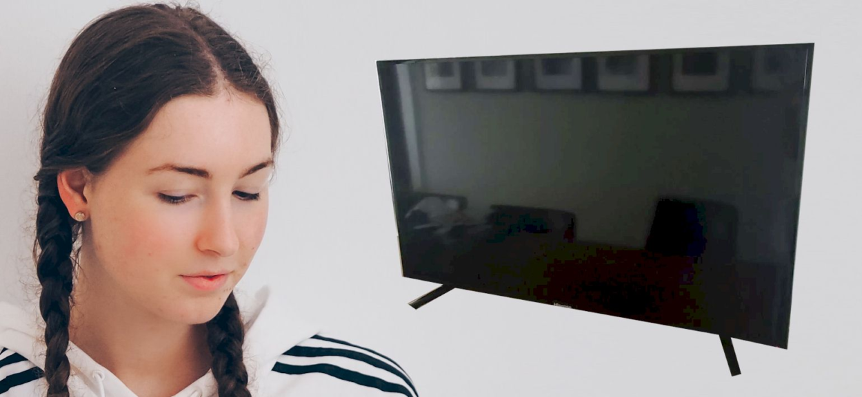 A girl standing beside a TV