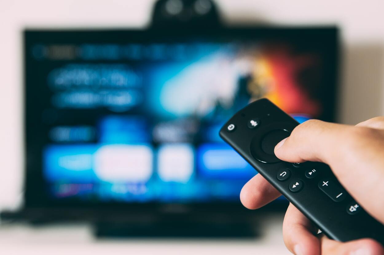 TV remote in hand with TV in background