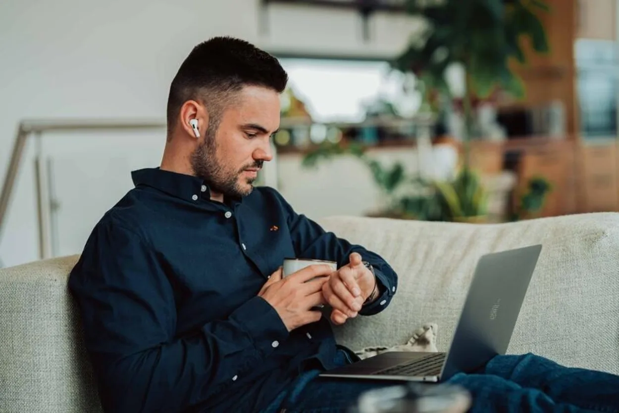 A person using his AirPods with his Macbook Pro