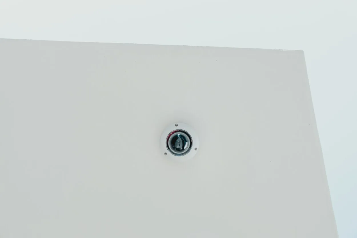 White dome security camera mounted on a white wall.