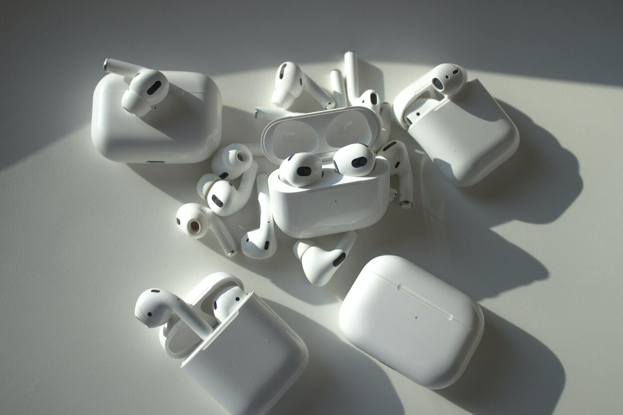 Multiple White Apple AirPods and AirPods Pro on top of a white table.