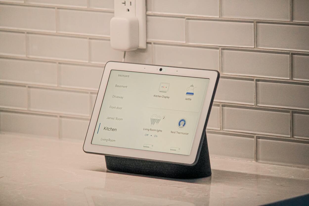 A modern smart thermostat being controlled by a tablet