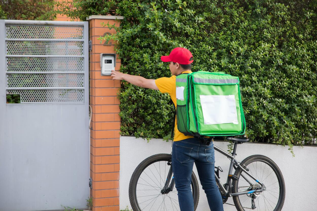 A Delivery man trying to ring a smart doorbell