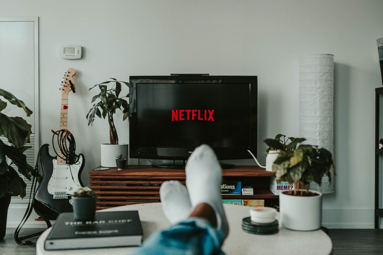 A TV with Netflix on display and a man wearing white socks
