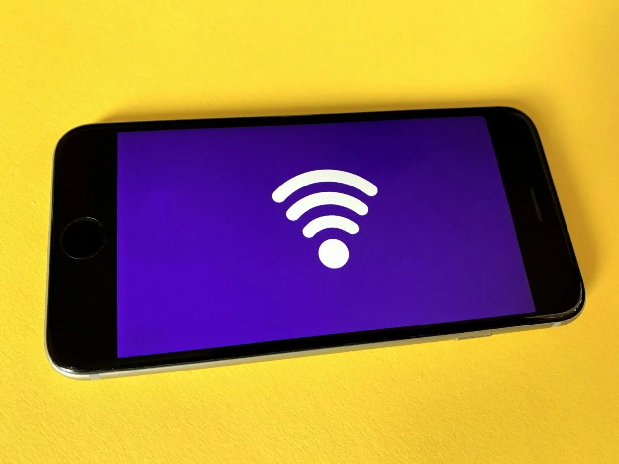 A phone displaying Wi-Fi symbol on purple background