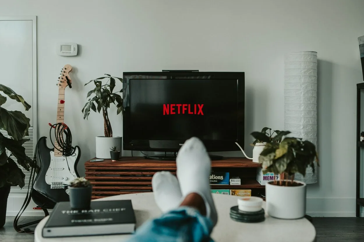 A person wearing white socks and a TV with Netflix displayed on 