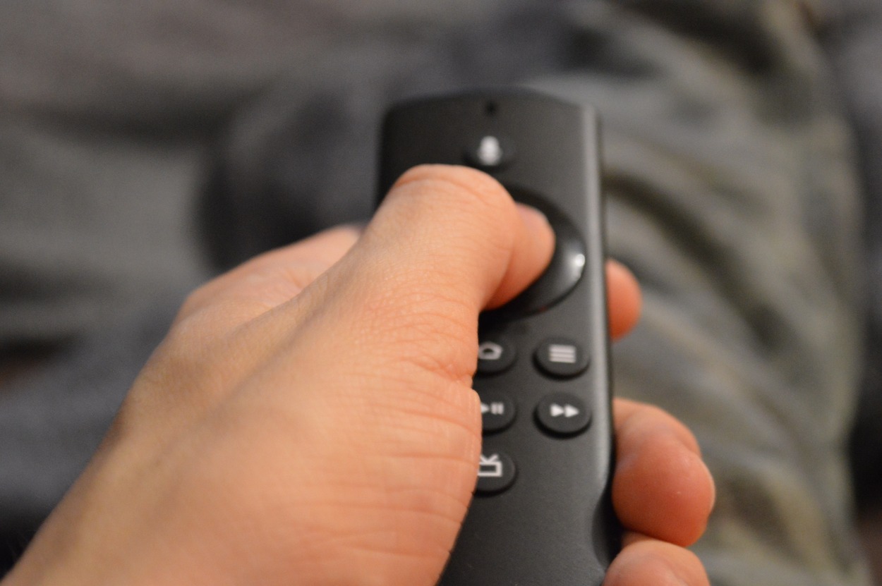 A hand holding a tv remote and pressing a button