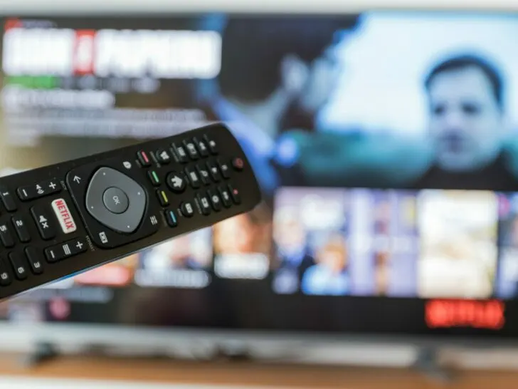 A remote with a TV displaying Netflix on the background