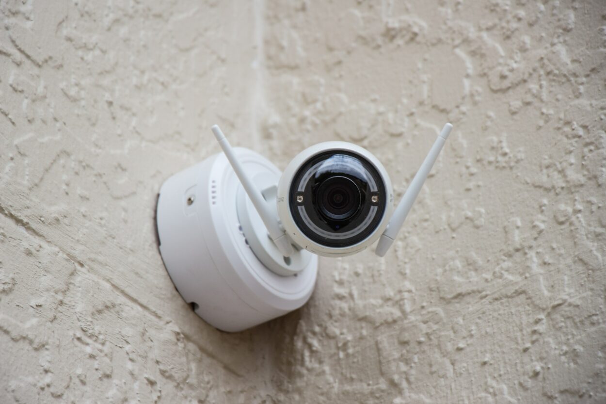 A white colored CCTV camera installed on a grainy wall