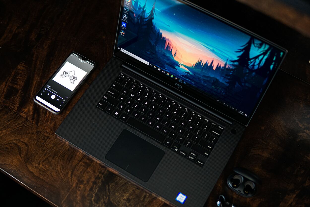 Dell laptop with phone and earbuds in the background.