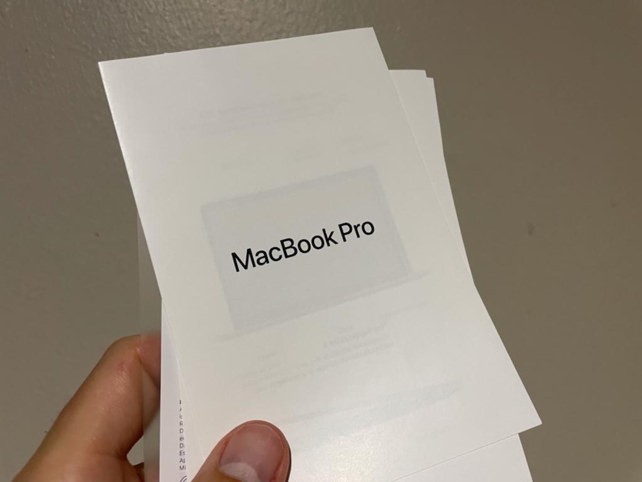 A person holding paper which has written MacBook Pro on it