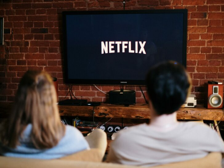 Two people facing the TV displaying the Netflix logo