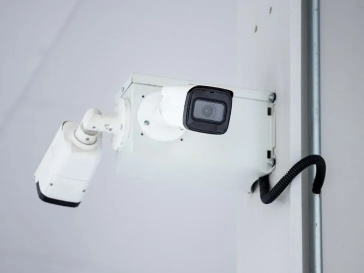 Two security camera mounted on a wall looking in different directions