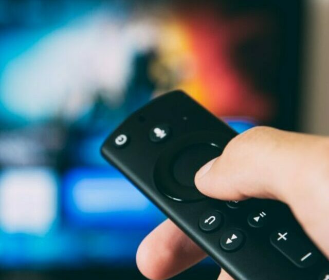 A person pointing a remote towards the TV