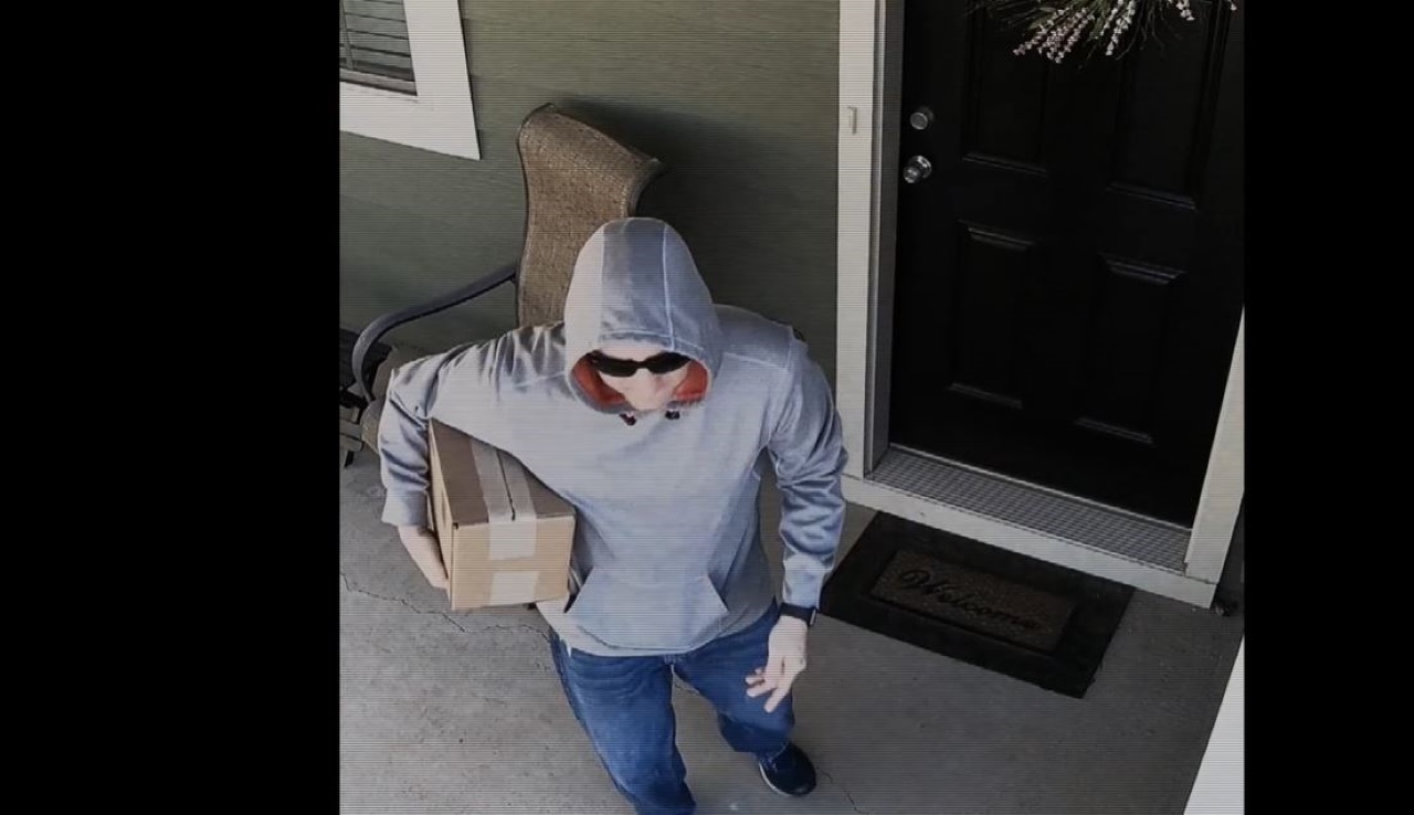 A guy standing in front of the door with a package