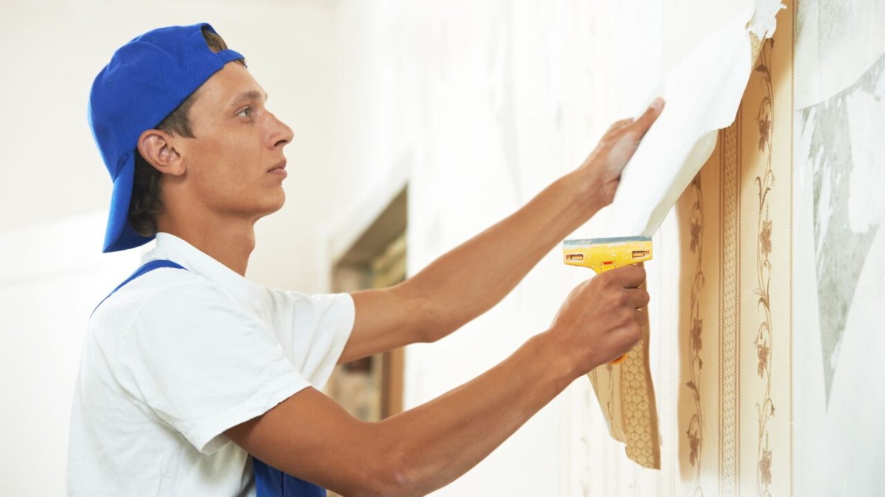 Painter peeling paint off from the wall.