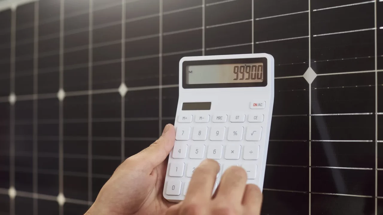 close up of man hands holding calculator and solar panels