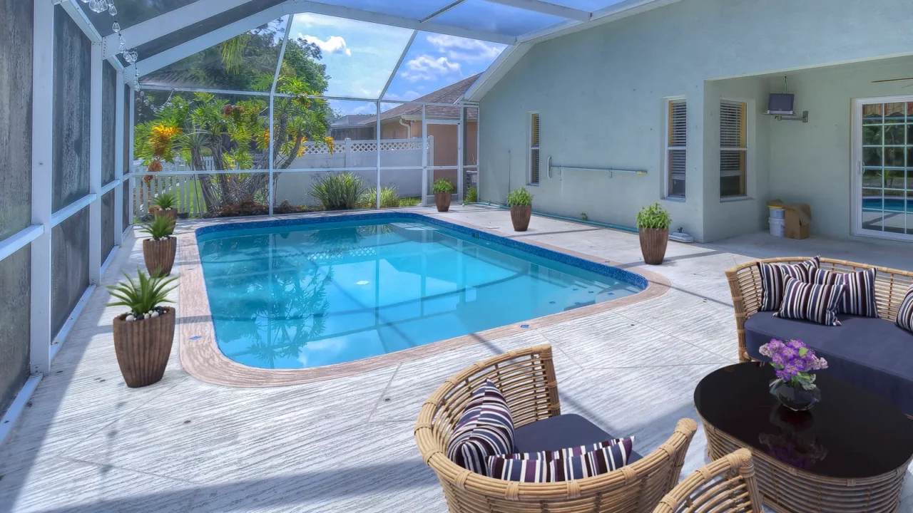 Backyard view of a modern house with large swimming pool, chairs and artificial grass.