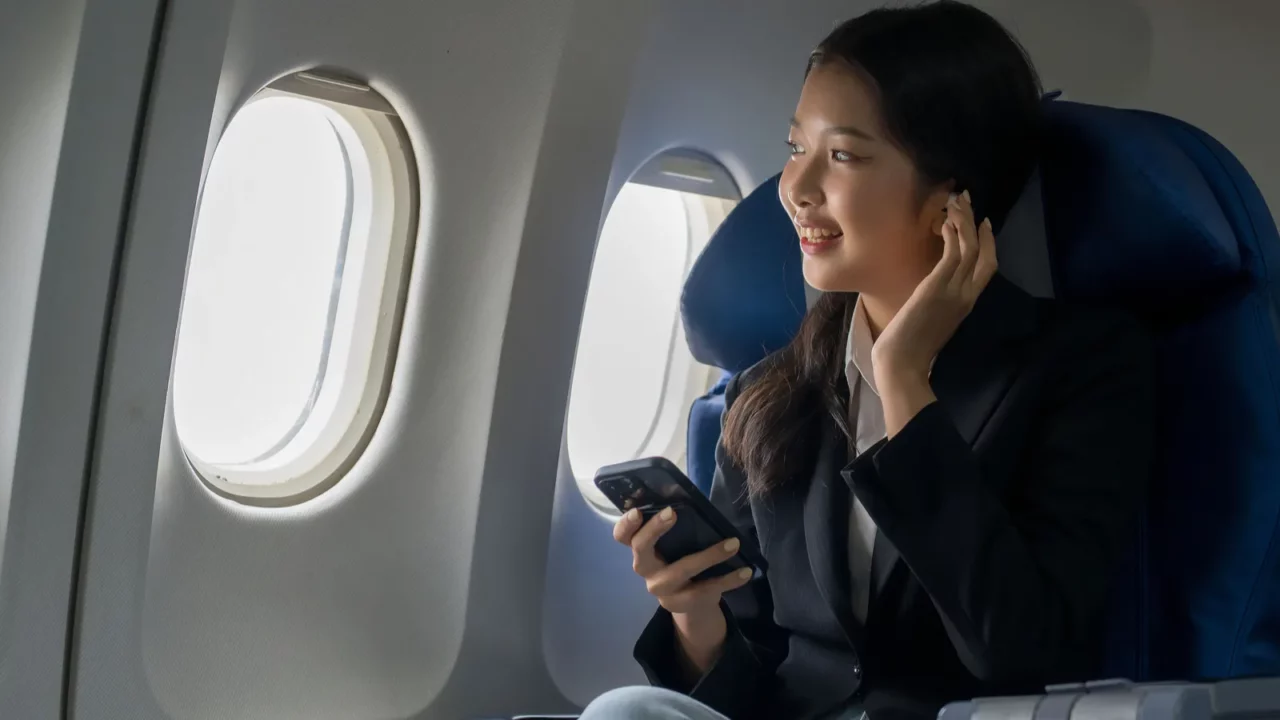 This image depicts a woman seated in a commercial airplane cabin, likely during travel.