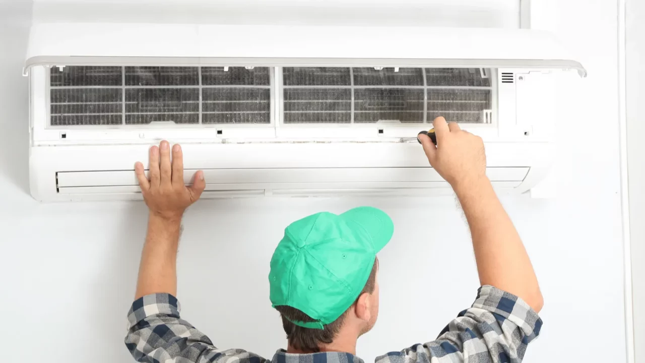 Male Technician Repairing a Modern indoor Air Conditioner.