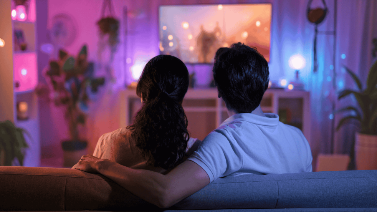 Happy family watching TV, movies in the evening at home. Couple spending time together.