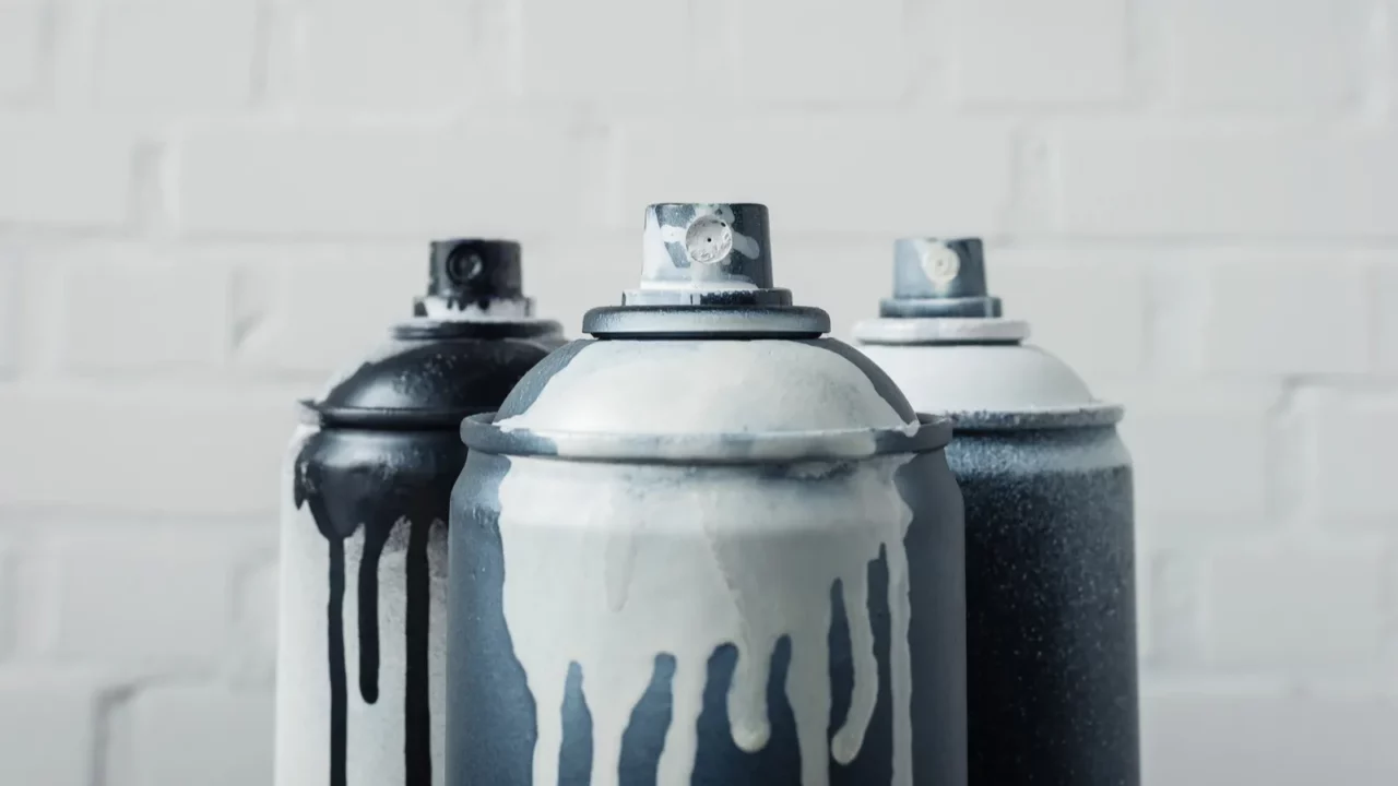 close up view of spray paint in cans with brick