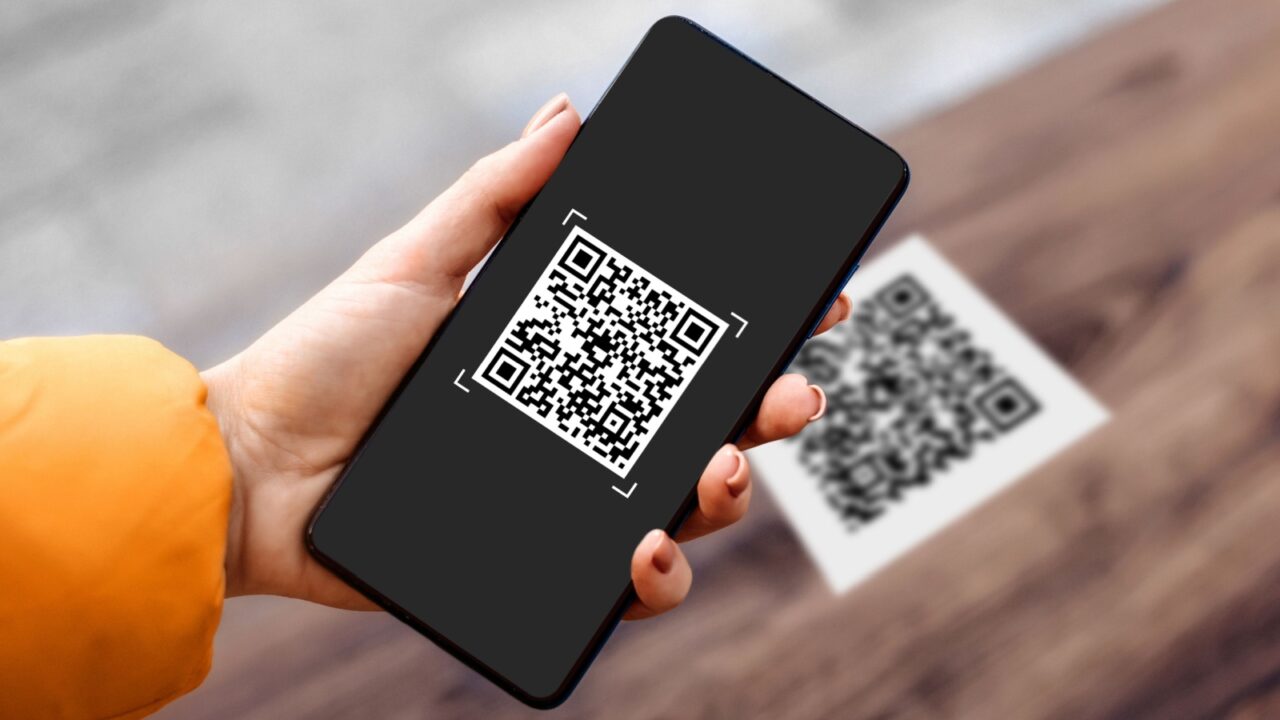 Female hand holding black mobile phone with qr code on the screen, scanning the qr code.