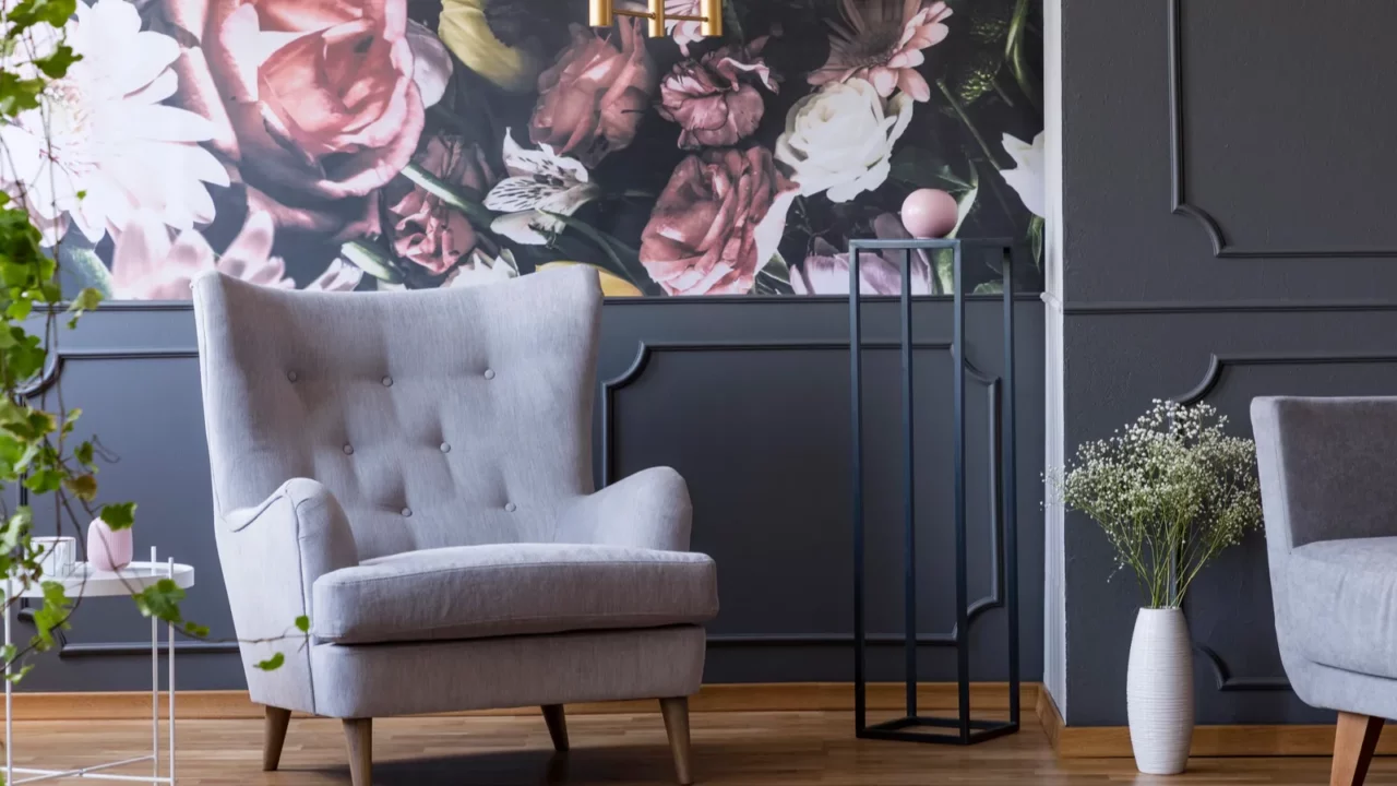 grey armchair against flowers wallpaper in dark living room interior