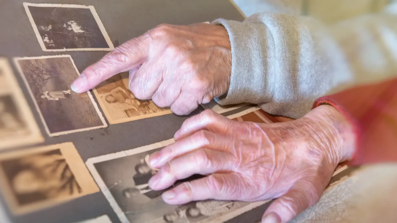 elderly couple hands looking at old pictures album at home