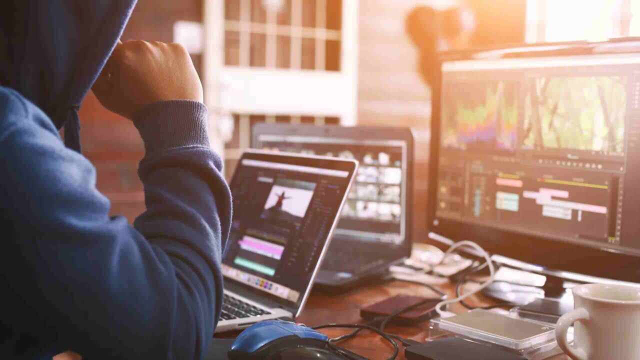 Close-cropped image showing a freelancer's focused workspace with laptop and editing tools.