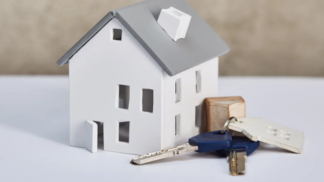 house model on white table with keys near grey textured